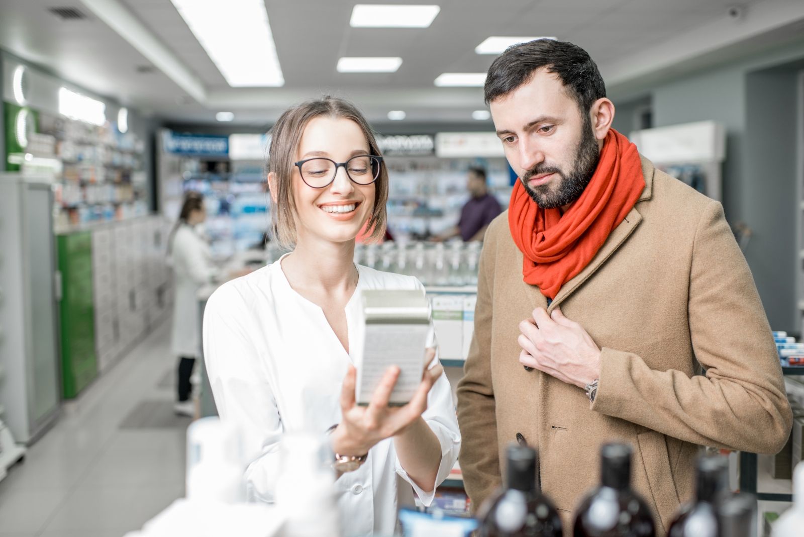 Une conseillère en pharmacie présente un produit à un client